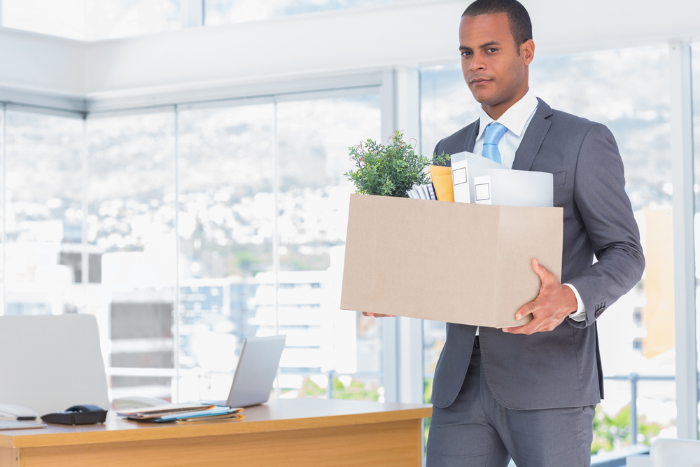 Sad businessman leaving his company while he is holding a box-1
